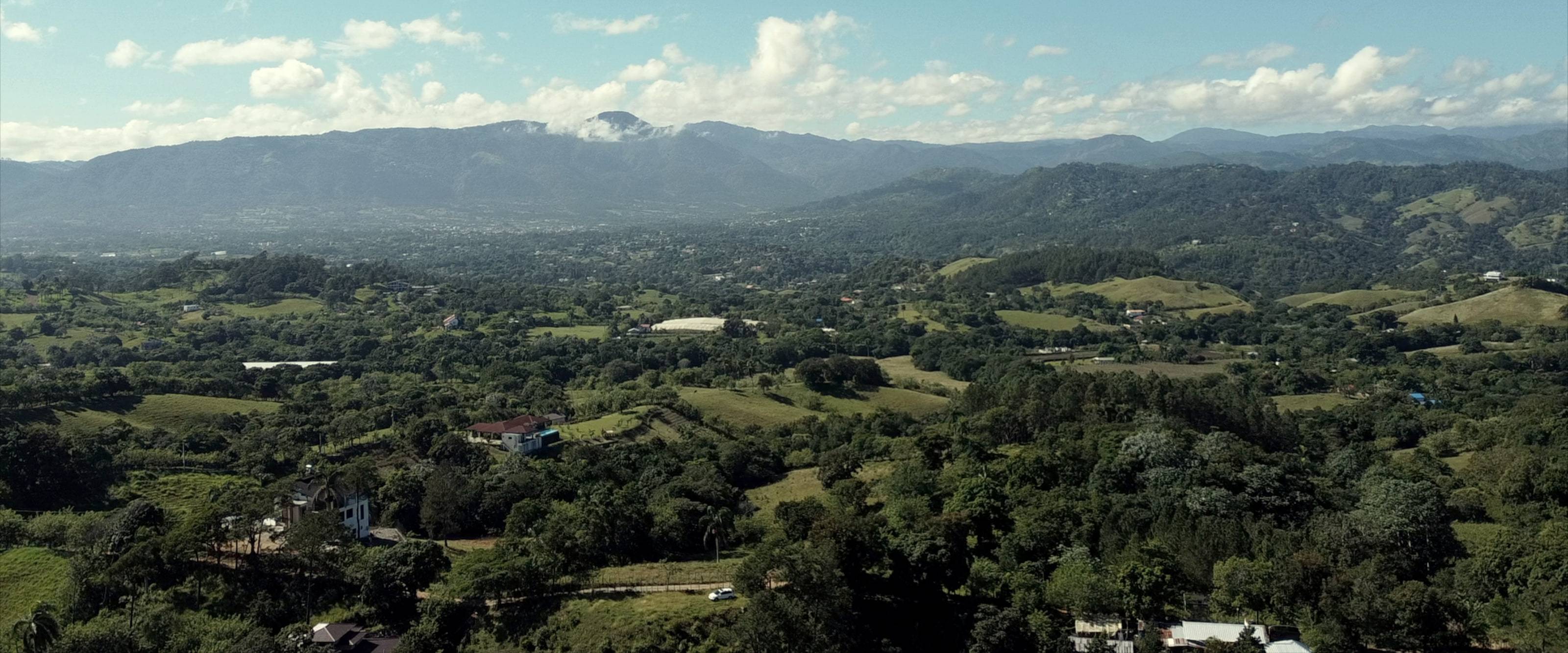 La cordillera de cumbre dentada, con niebla prendida en su ladera, que dio origen a la marca Bruma, sobre el valle de Jarabacoa